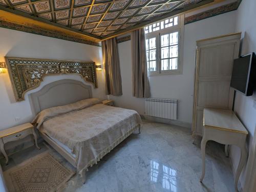 Dar Hamouda Guest House - Médina de Tunis في تونس: غرفة نوم فيها سرير وتلفزيون