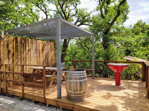 a wooden deck with a picnic table and a barrel at Lodges du Ushuaïa Villages Camping les 4 Saisons in Grane