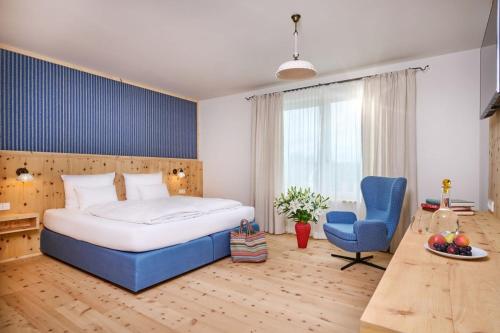 een slaapkamer met een groot bed en een blauwe stoel bij Hotel Der Einrichter in Straubing