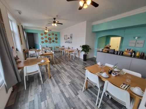 Beach Hotel Torbay في بينتون: مطعم بطاولات وكراسي خشبية وجدران خضراء