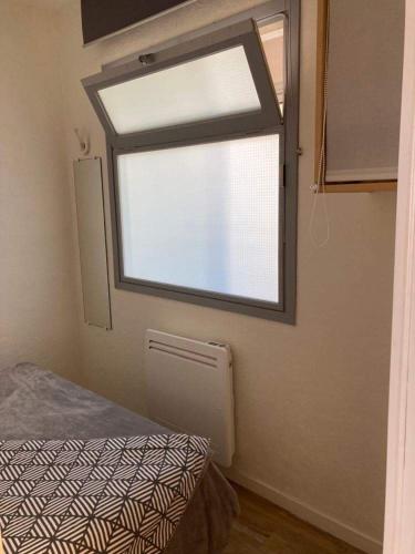 Cette petite chambre dispose d'une fenêtre et d'un lit. dans l'établissement Appartement idéalement placé sur le port, à La Turballe