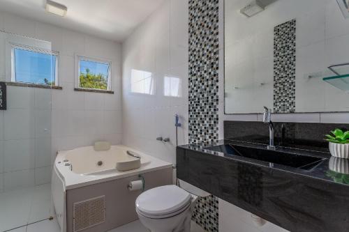 a bathroom with a sink and a toilet and a tub at Casa incrível com 04 suítes - 5 min de Itacoatiara in Niterói