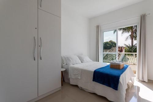 a white bedroom with a bed and a window at Casa incrível com 04 suítes - 5 min de Itacoatiara in Niterói
