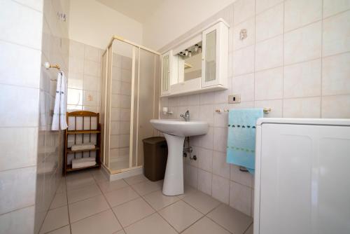 Baño blanco con lavabo y espejo en Casa vacanze Ogliastra, en Girasole