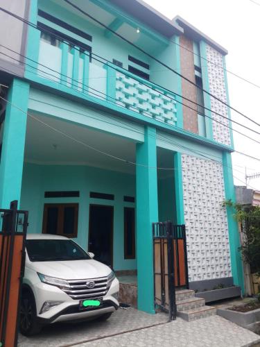 une voiture blanche garée devant une maison dans l'établissement Guest House Murah -homestay - Kos harian, 