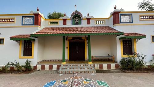 a building with a door and a bench in front at Marutham Village Resort in Mahabalipuram