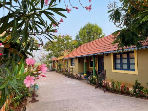 a house with a red roof and some flowers at Marutham Village Resort in Mahabalipuram