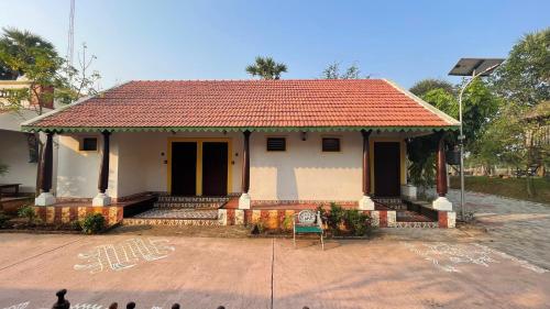 a small white house with a red roof at Marutham Village Resort in Mahabalipuram