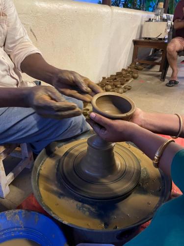 a person making a pot on a pottery wheel at Marutham Village Resort in Mahabalipuram