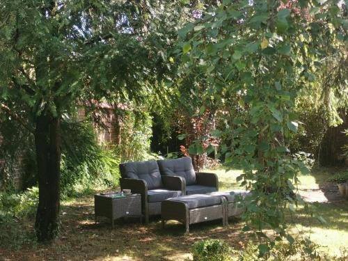 a couch sitting in the yard under a tree at La Maison de Ville in Compiègne