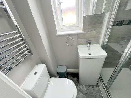 uma casa de banho branca com um WC e um lavatório em Deluxe Ringwood Rooms em Hackbridge