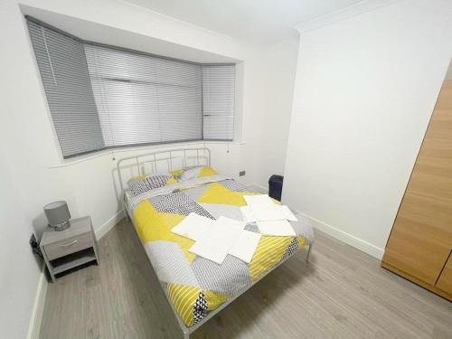 a bedroom with a bed with a yellow and white quilt at Deluxe Ringwood Rooms in Hackbridge