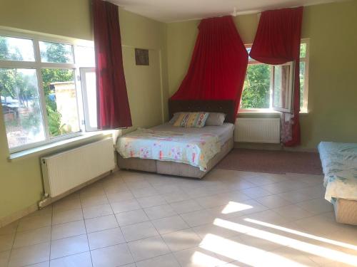 a bedroom with a bed with red curtains and windows at KALECİK OTEL in Kalecik