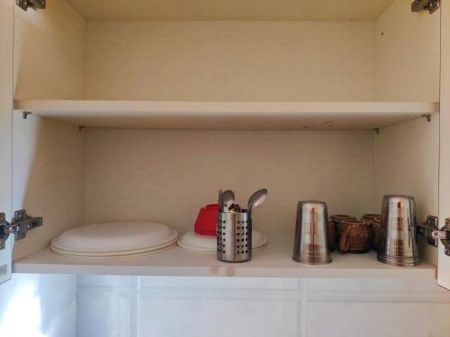 a shelf with plates and utensils in a kitchen at Luxurious 3BHK Urban Retreat Homestay in Jaipur