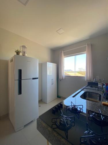 a kitchen with a white refrigerator and a counter top at AP Residêncial Delior - Parada do Jalapão e Aromaterapia in Palmas