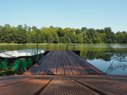 a wooden dock with a boat on a lake at Beniaskie! Agroturystyka nad Jeziorem in Miłakowo