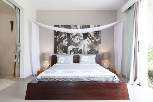 a bedroom with a bed with a poster of three men at Villa KMEA 4 in Seminyak