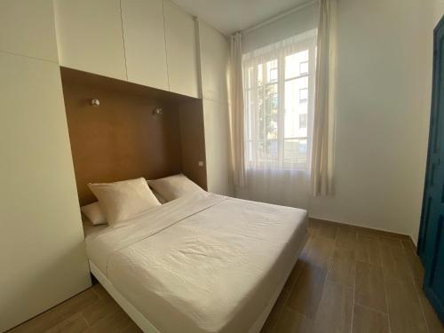 une chambre avec un grand lit blanc avec une fenêtre dans l'établissement 2 pièces / neuf - Ajaccio centre - Place Miot / Albert 1er, à Ajaccio