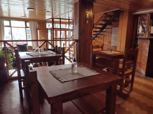 un restaurante con mesas y sillas de madera y ventanas en Hotel Curru Leuvu en San Carlos de Bariloche