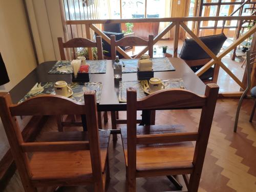 Hotel Curru Leuvu في سان كارلوس دي باريلوتشي: طاولة طعام مع كراسي وطاولة عليها أطباق