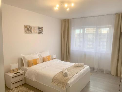 a white bedroom with a bed and a window at JAD - Family Apartments & Studios in Braşov