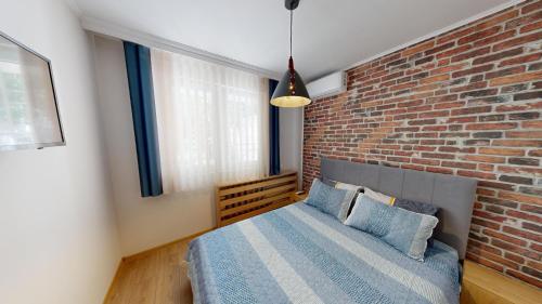 a bedroom with a brick wall and a bed at Апартамент в топ център София 5 Corners in Sofia