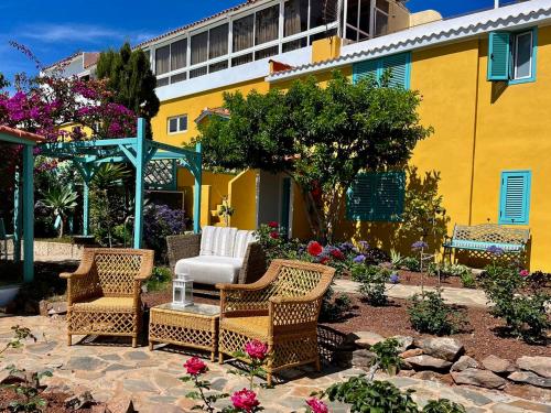 un patio con sedie in vimini e un edificio giallo di La Finquita - Adeje ad Adeje