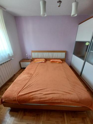 a bedroom with a large bed with an orange blanket at Apartman JAGODA in Varaždin