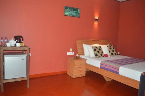 a bedroom with orange walls and a bed and a night stand at Amazon Cabanas in Tissamaharama