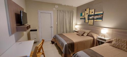 een hotelkamer met 2 bedden en een televisie bij Casas Noviembre in Plottier