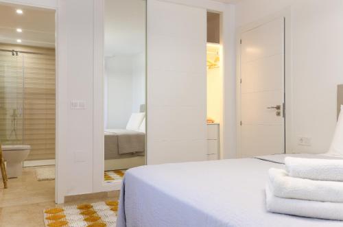 Habitación blanca con cama y baño. en Luxury with pool view - Playa Real beachfront, en Marbella