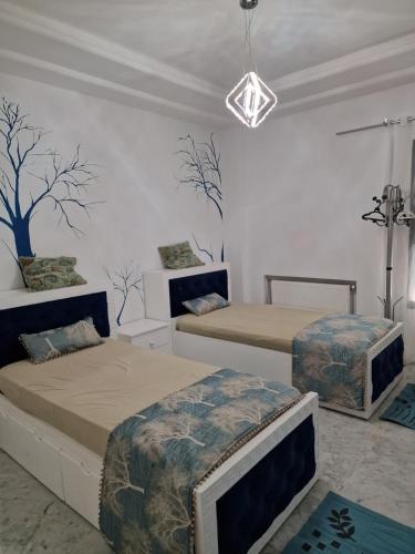 a bedroom with two beds and a chandelier at Appart de Luxe au Centre Urbain Nord in Tunis