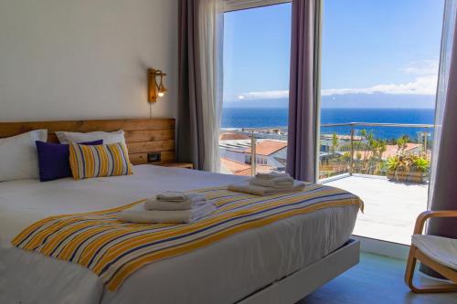 a bedroom with a bed with a view of the ocean at Blue Planet São Jorge Azores - RRAL nº 1341 in Velas