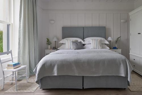 a white bedroom with a large bed and a chair at Achnahatnich House in Aviemore