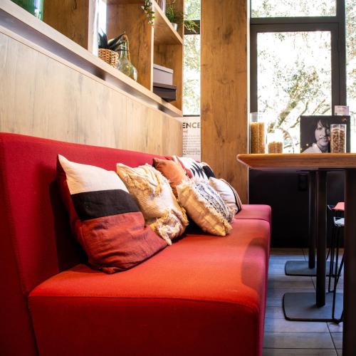 a red couch with pillows on top of it at ibis Aix en Provence in Aix-en-Provence
