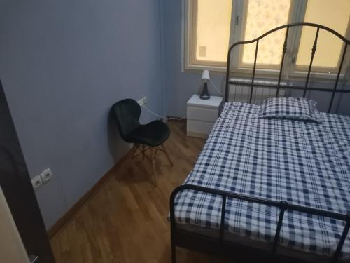 a bedroom with a bed and a chair and a window at Cozy palace in Belgrade