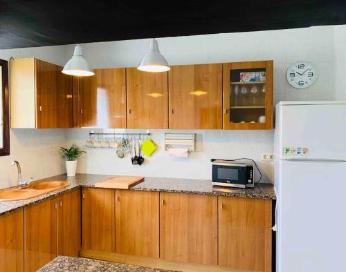 uma cozinha com armários de madeira, um lavatório e um micro-ondas em Cal Frare, Colomers em Colomés