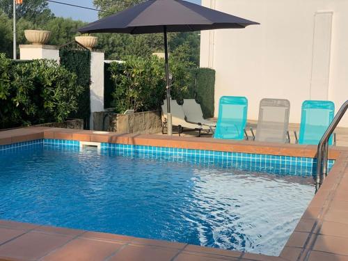 uma piscina com duas cadeiras e um guarda-sol em Cal Frare, Colomers em Colomés