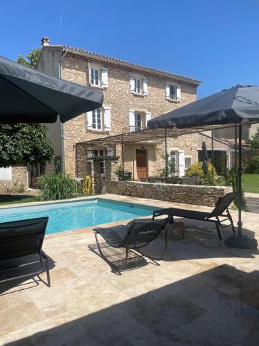 a swimming pool with two chairs and an umbrella at Provenzalisches Landhaus Les Martinets am Fuße des Mont Ventoux in Villes-sur-Auzon