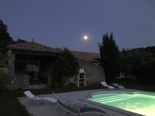 a pool with chairs and a house with the moon at Roc du Lapin in Sainte-Colombe-de-Villeneuve