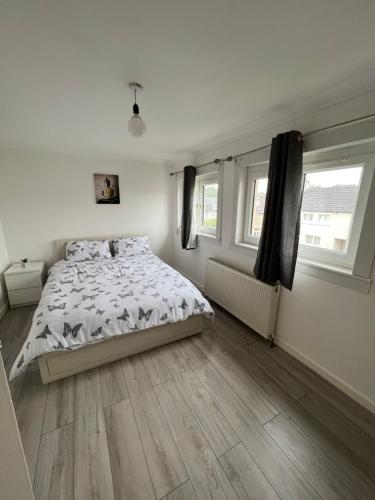 a white bedroom with a bed and two windows at 2 Bedrooms house,kitchen,bathroom,free parking in Mount Vernon