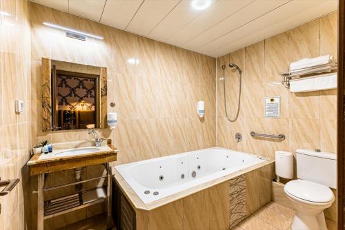 a bathroom with a tub and a toilet and a sink at Spa House Boutique Hotel - Petach Tikwa in Petaẖ Tiqwa