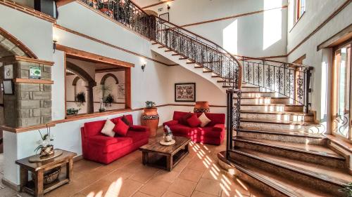 sala de estar con escalera y sofás rojos en Maria Bonita Hotel, en Villa de Leyva