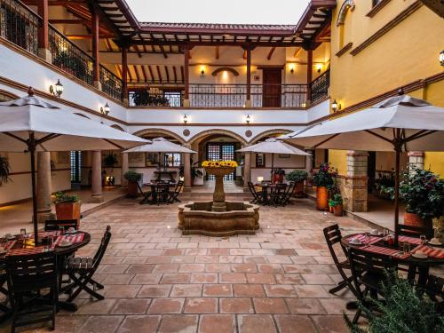 un patio interior con una fuente, mesas y sombrillas en Maria Bonita Hotel en Villa de Leyva