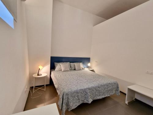 Dormitorio blanco pequeño con cama y mesa en Casa Alferi by TraMonti Apartments, en LʼAquila