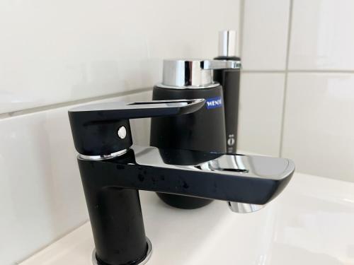 a black faucet in a public bathroom at Brightside Apartment in Kristiansand