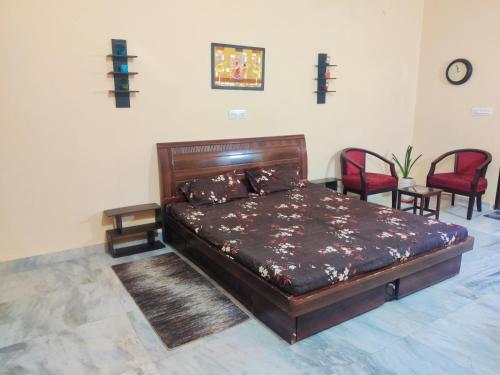 een slaapkamer met een groot houten bed met 2 stoelen bij Luxurious 3BHK Urban Retreat Homestay in Jaipur