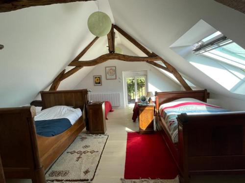 - une chambre mansardée avec 2 lits et une fenêtre dans l'établissement Gîte La Coulée des Robins, à Continvoir