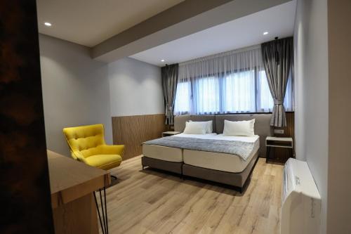 a bedroom with a bed and a yellow chair at Vila Kace in Korçë