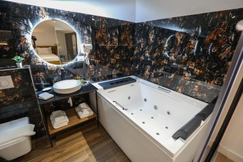 ein Badezimmer mit einer Badewanne, einem Waschbecken und einem Spiegel in der Unterkunft Vila Kace in Korçë